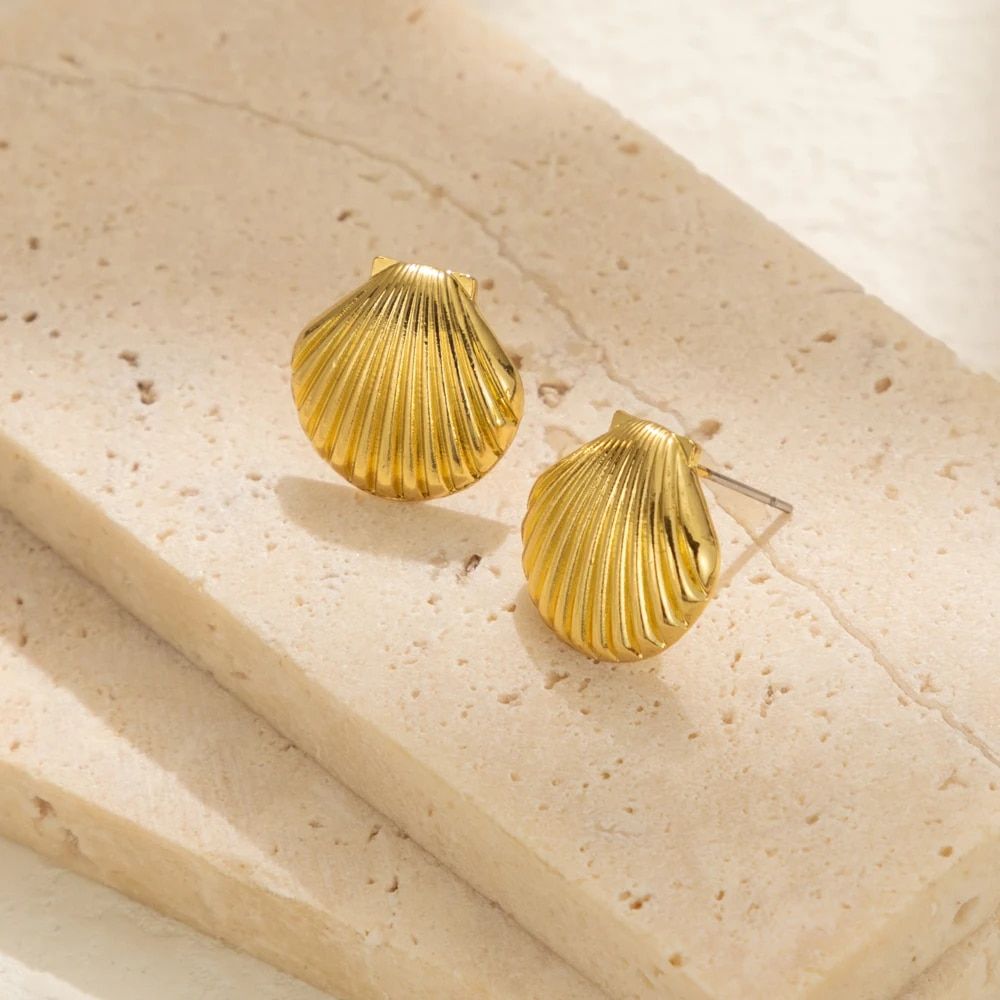 Vintage shell design stud earrings for women on a beige stone surface, highlighted by natural light and embodying new fashion style.