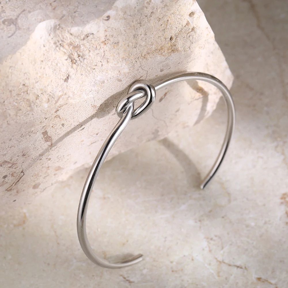 Twist Knot Stainless Steel cuff bracelet with a knot design in the latest womens fashion, displayed on a stone surface.