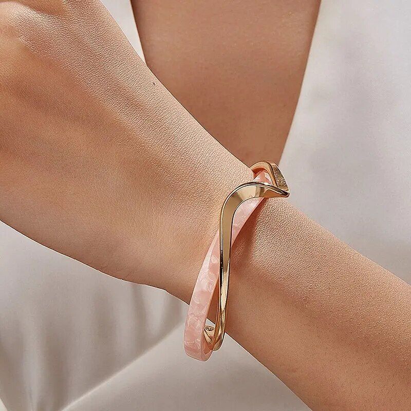 Close-up of a new Geometric Metal Charm Bracelet for Women with a twist design worn on a woman's wrist against a white background.