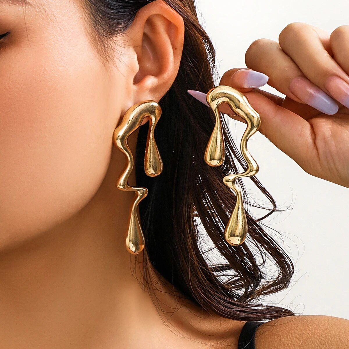 Close-up of a woman showcasing new fashion with Vintage Gold Geometric Water Drop Earrings, highlighting her hand adjusting one earring with a focus on the jewelry and partial view of her face.