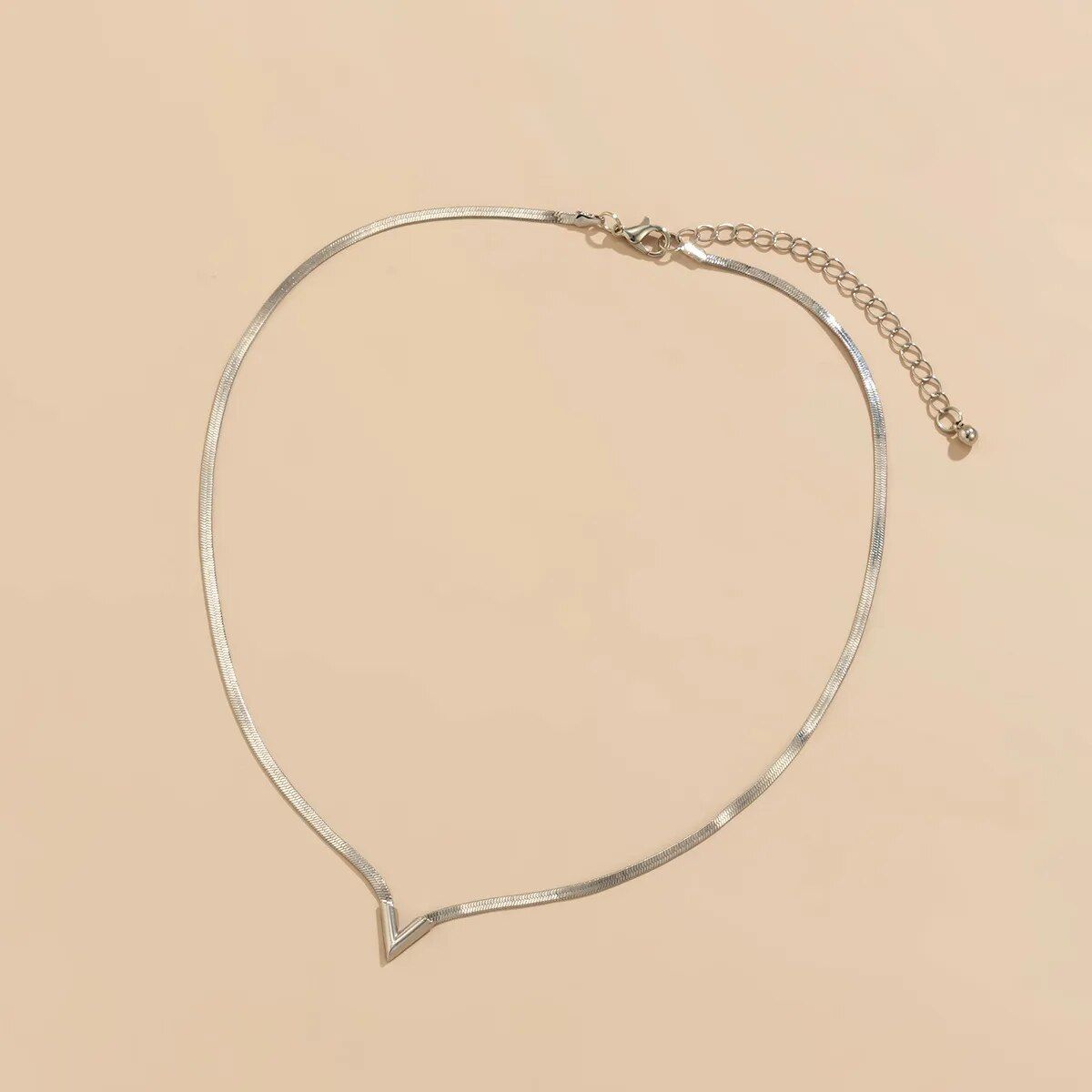 Elegant V-Shaped Flat Snake Chain Necklace with a v-shaped pendant, a new fashion accessory, on a beige background.