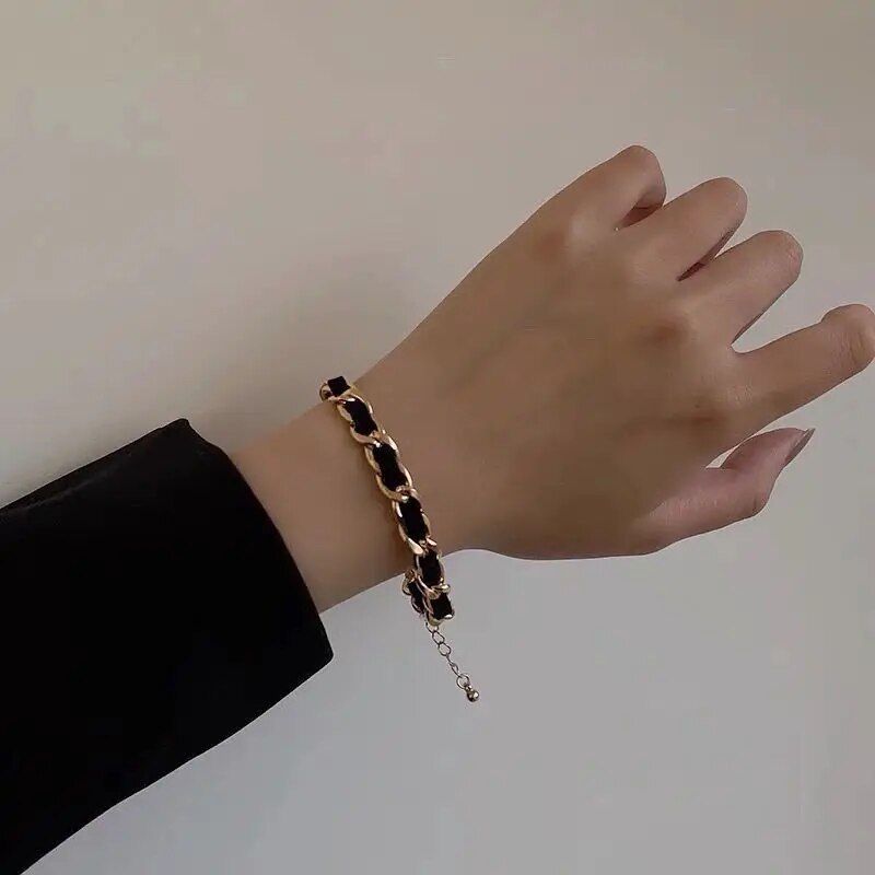 A hand wearing a black sleeve and an Elegant Vintage Rose Gold Black Woven Bracelet, representing womens fashion, against a light background.