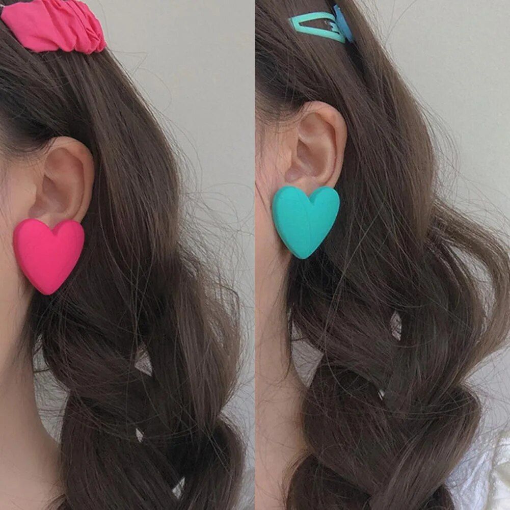 Split image showing a woman's ear adorned with colorful heart-shaped acrylic earrings, featuring her brown wavy hair as a fashionable accessory.