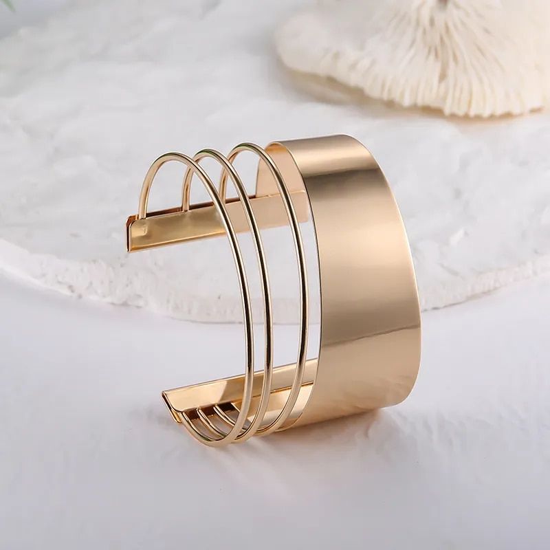 A Women's Bohemian Gold-Plated Geometric Cuff Bangle with a sleek, modern design featuring multiple bands is a new fashion accessory on a white surface.
