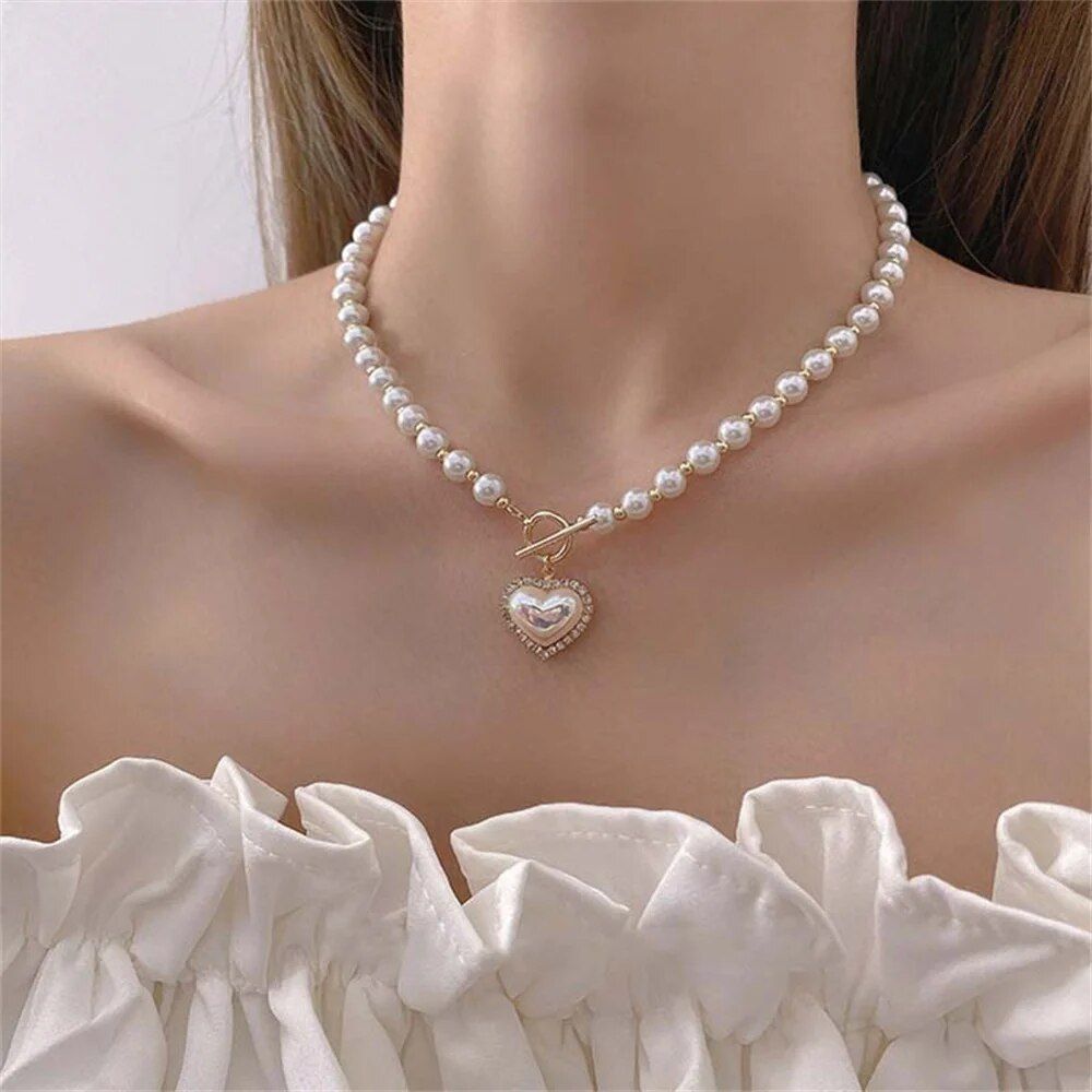 Close-up of a woman wearing a Vintage Heart Pendant Pearl Necklace, paired with a white ruffled top as an elegant fashion accessory.