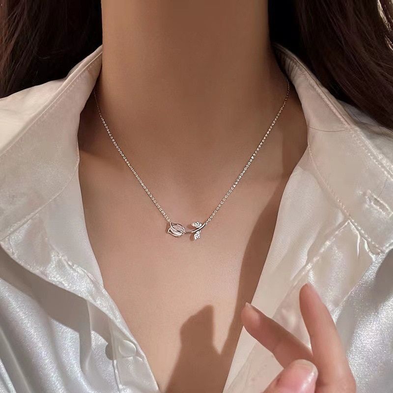 A close-up of a woman wearing a Classy Microinlaid Tulip Pendant Necklace on a chain necklace, complemented by a white satin blouse in the latest fashion style.