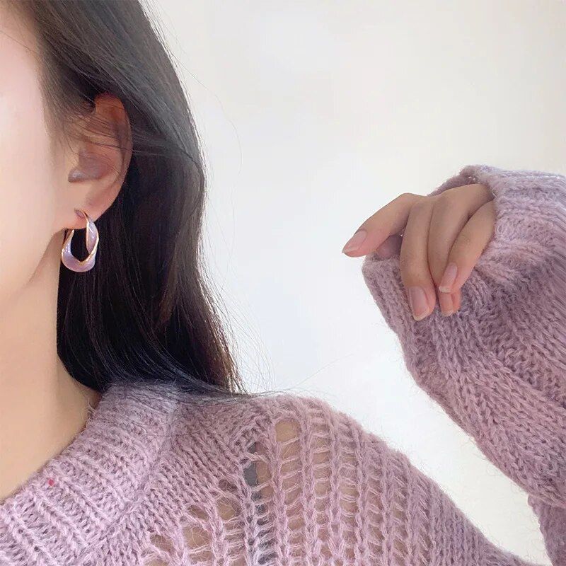 Close-up of a woman wearing a lavender knitted sweater and Lavender Purple Twisted Hoop Earrings, focusing on her ear and shoulder, against a white background. This fashion accessory highlights the latest in women's style.