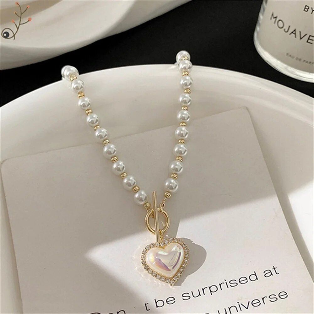 Vintage heart pendant pearl necklace with a heart-shaped pendant, showcasing women's fashion, on a white surface.