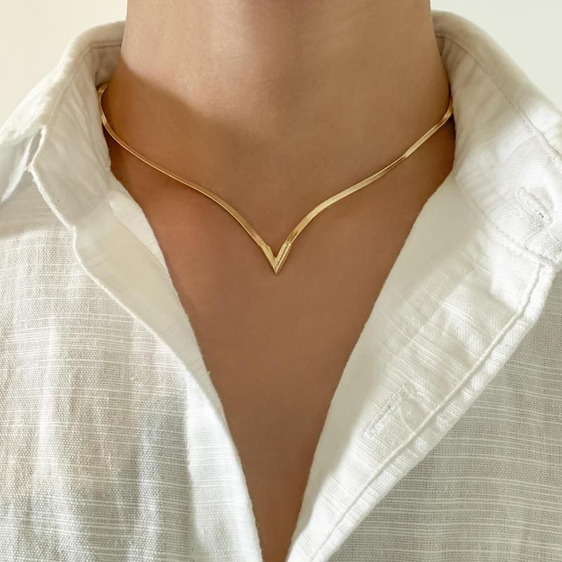 Close-up of a person wearing a white shirt with a v-neckline, adorned with an Elegant V-Shaped Flat Snake Chain Necklace, showcasing women's fashion.
