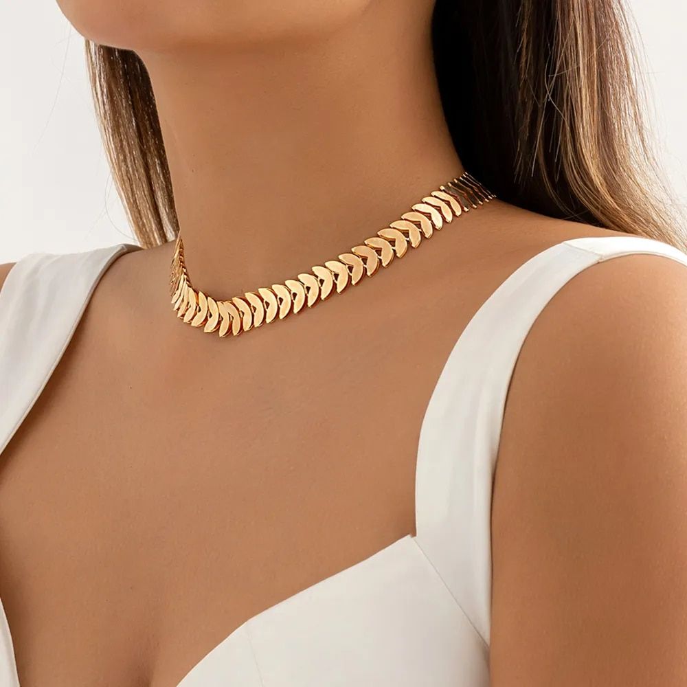 Woman wearing a Gold Petal Choker Necklace for Women with a white dress, close-up on the necklace and neckline, showcasing new fashion trends.