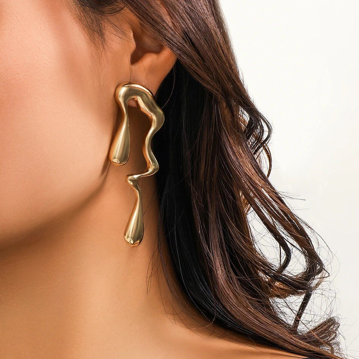 Close-up of a woman wearing a unique, Vintage Gold Geometric Water Drop earring, focusing on her ear and the lower part of her face with visible brunette hair. This fashion accessory highlights contemporary fashion trends.