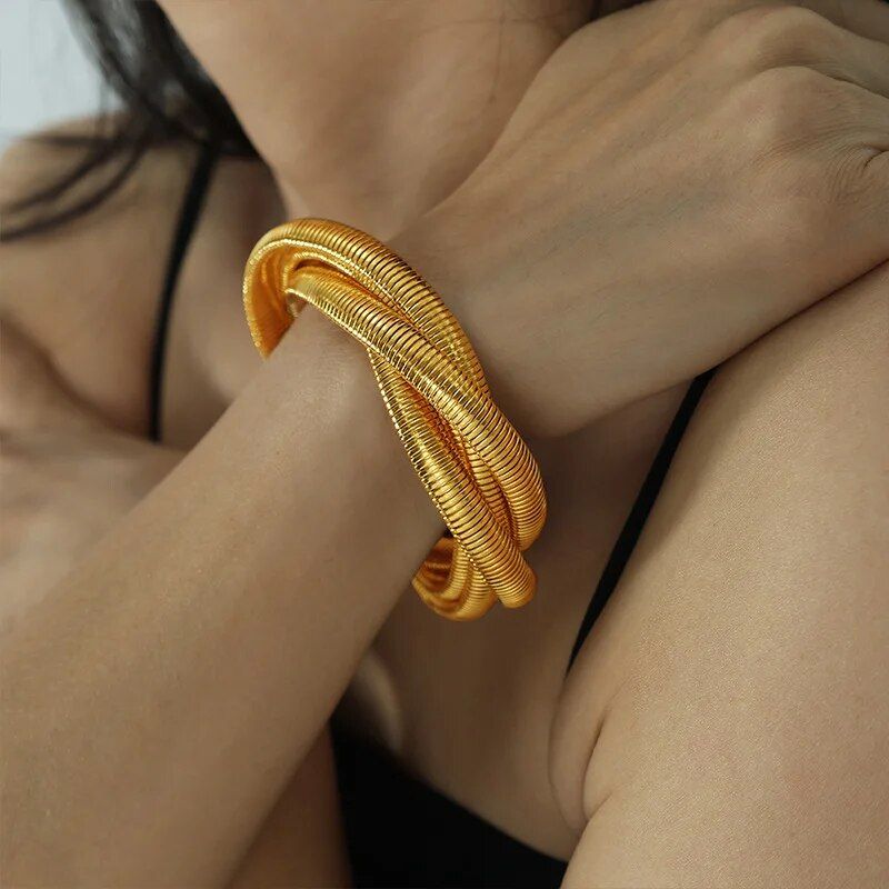 A close-up of a woman wearing a Trendy Punk Style Gold-Plated Geometric Womens Bangle on her wrist, resting her hand on her shoulder. This piece is a stunning example of the latest in women's fashion accessories.