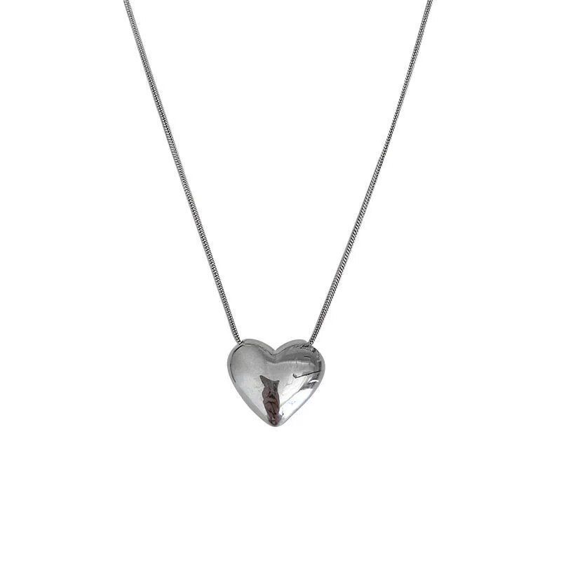 Gothic Trendy heart-shaped pendant necklace with an embedded brown leaf detail, reflecting the latest womens fashion trends, hanging from a fine silver chain, isolated on a white background.