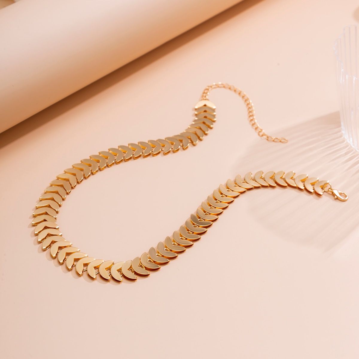 Gold Petal Choker Necklace for Women displayed on a pale pink surface with soft shadows, reflecting new fashion trends.