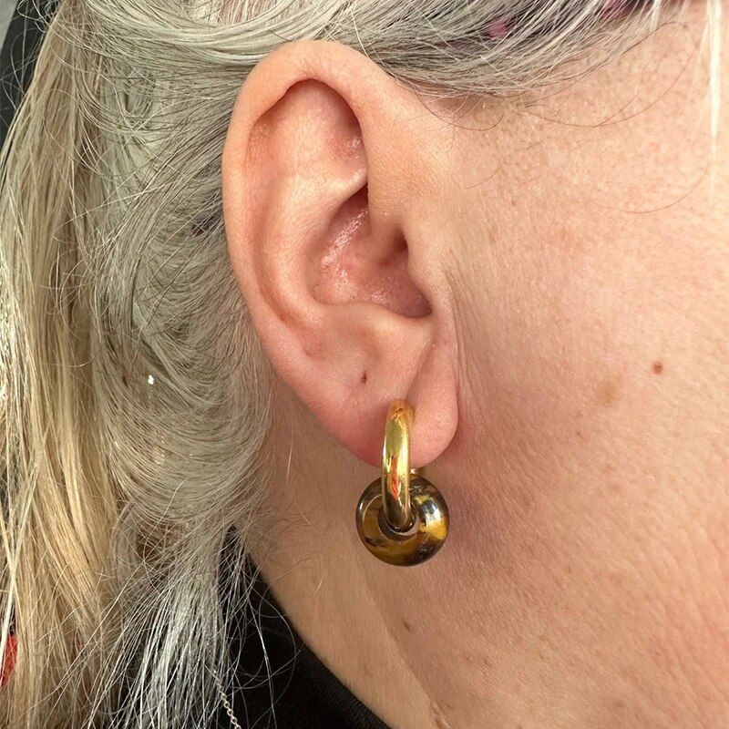 Close-up of a person's ear adorned with a Women's Natural Stone Hoop Earring, a striking fashion accessory. The person has white hair accented with hints of pink.
