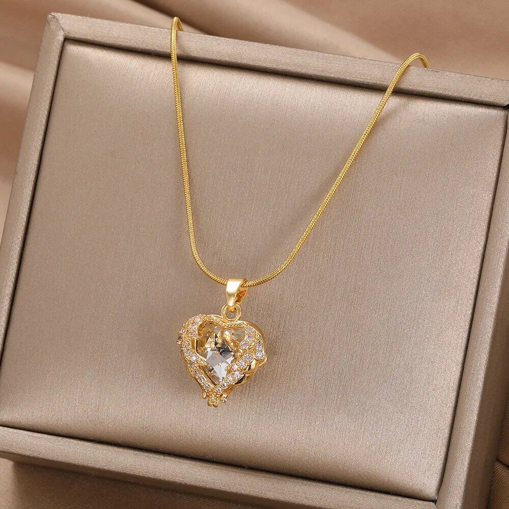 Gold-plated enamel red heart pendant necklace with a central gemstone, displayed in a beige jewelry box, epitomizing current fashion trends.