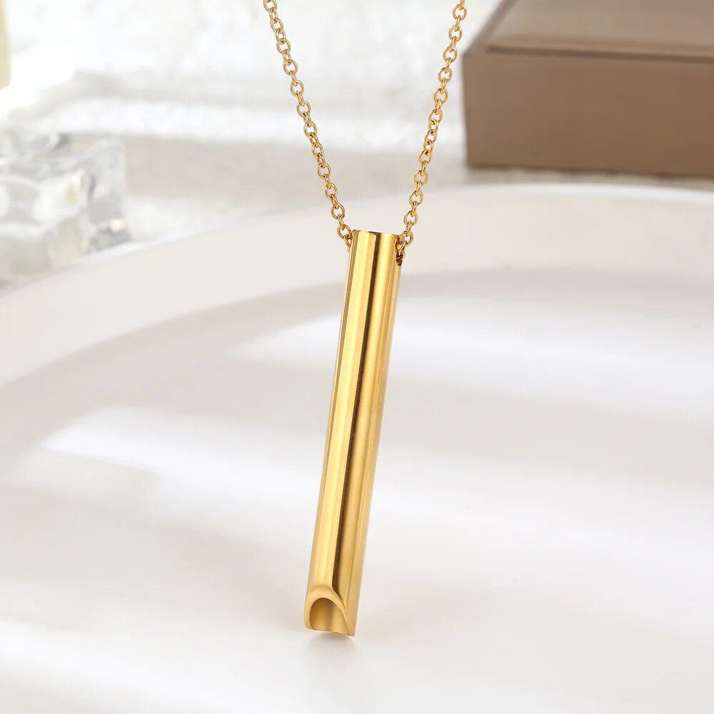 Stress Relief Breathing Necklace with a minimalist cylindrical design suspended from a delicate chain, displayed against a soft background, epitomizing current fashion trends.